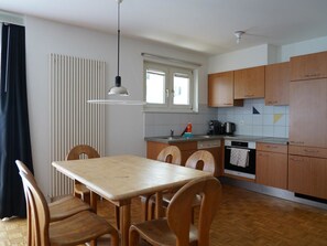 Eine kleine Küche mit Esstisch, Stühlen, einem Fenster und Holzschränken.