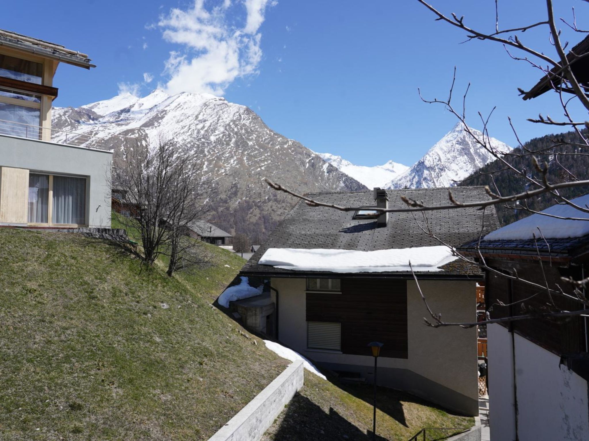 A residential area with a house, a small building, and a mountain in the background.