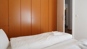 Un dormitorio con cama, armario y puerta que da a otra habitación.