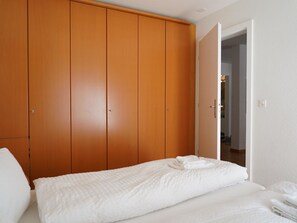 Ein Schlafzimmer mit Bett, Kleiderschrank und einer Tür zu einem anderen Raum.