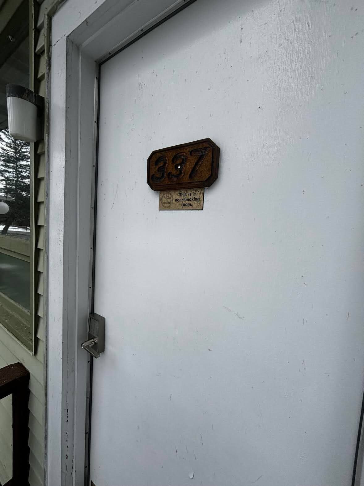 Porta com placa de identificação com o número '337' e aviso indicando 'Quarto proibido para fumantes'.
