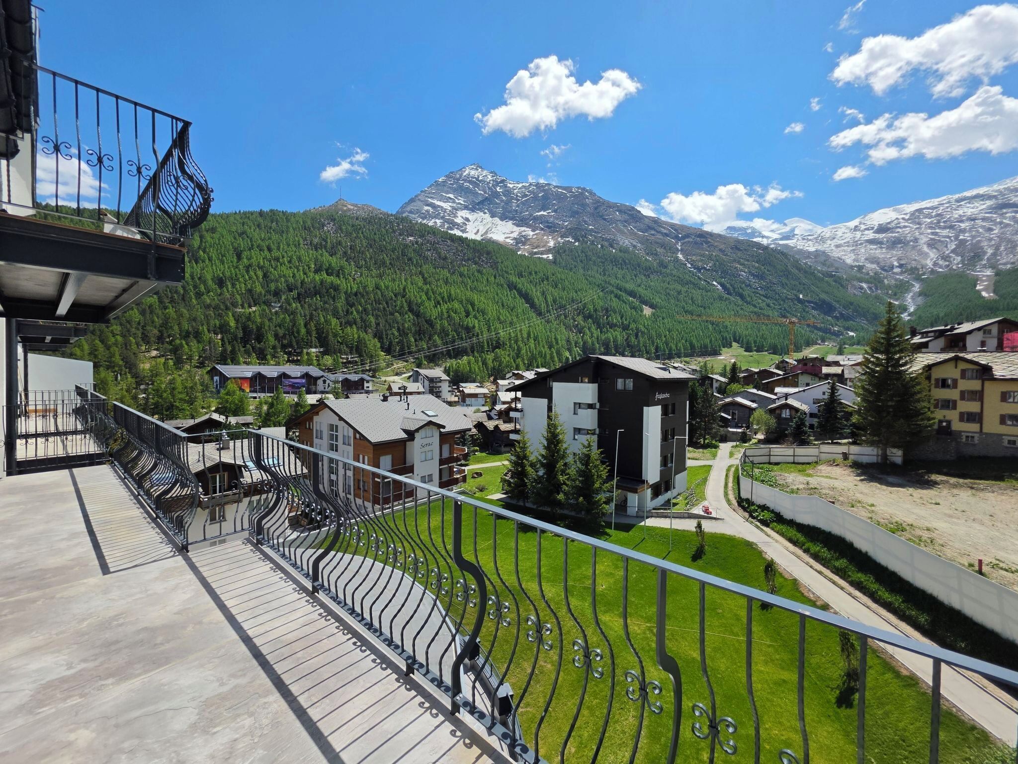 A residential area with houses, a balcony, and a mountain backdrop.