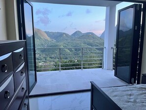 A balcony with a view of green hills and mountains. - Wake up to views of the Pitons, Sea & Soufriere from this  hillside villa. (Soufriere)