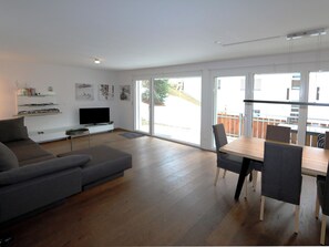 En moderne stue med sofa, fjernsyn og kunst på væggen.