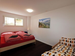 A bedroom with a bed, a chair, a window, and a painting on the wall. - Perrine 1 Appartement/Fewo Appartement/Fewo by Interhome (Saas-Fee)