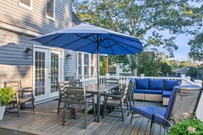 Eine Terrasse mit Tisch, Stühlen, einem blauen Sonnenschirm und einem blauen Sofa.