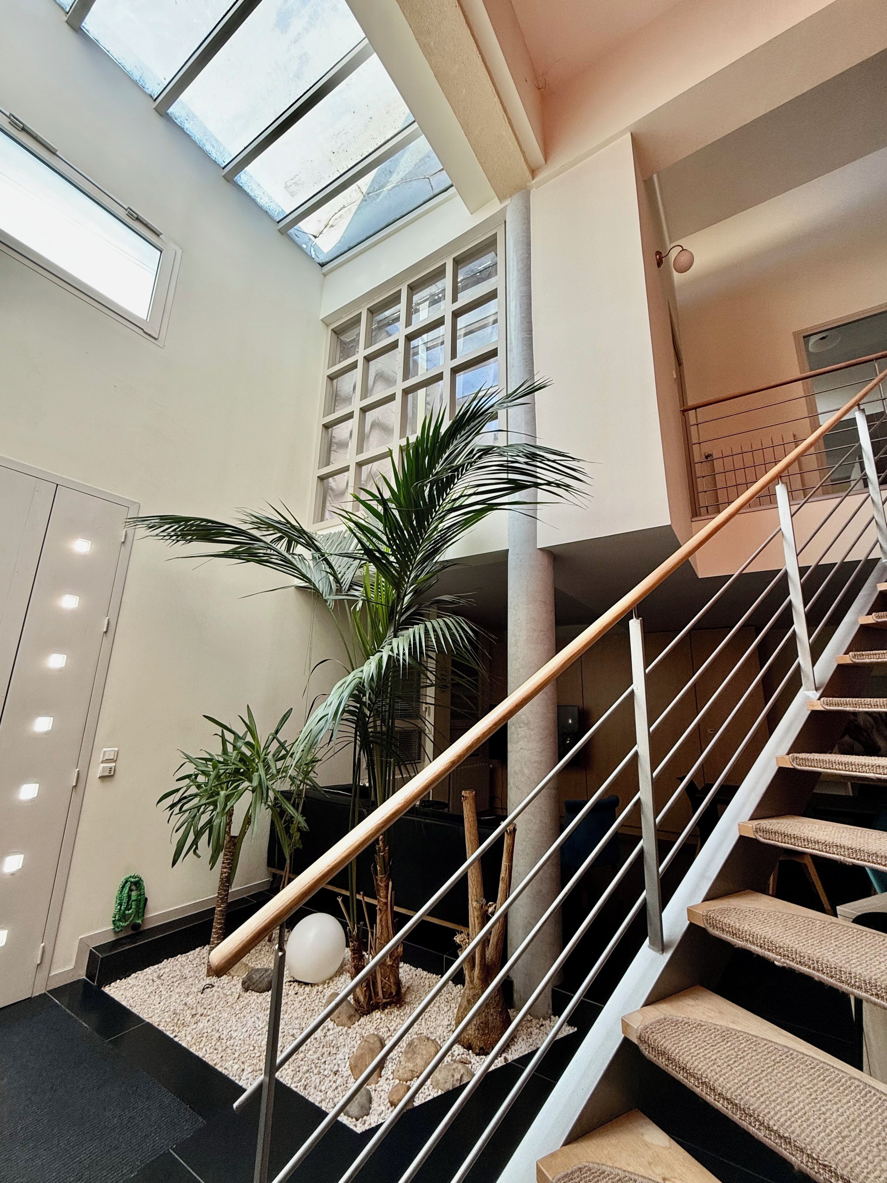 Een modern interieur met een trap, dakraam en kamerplanten.