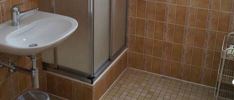 A bathroom with a shower, sink, and window.