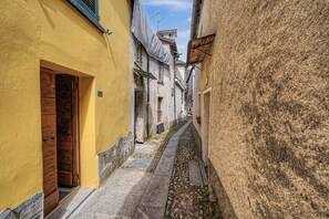 Un estrecho callejón flanqueado por edificios, con una puerta de madera a la izquierda y un sendero de piedra.