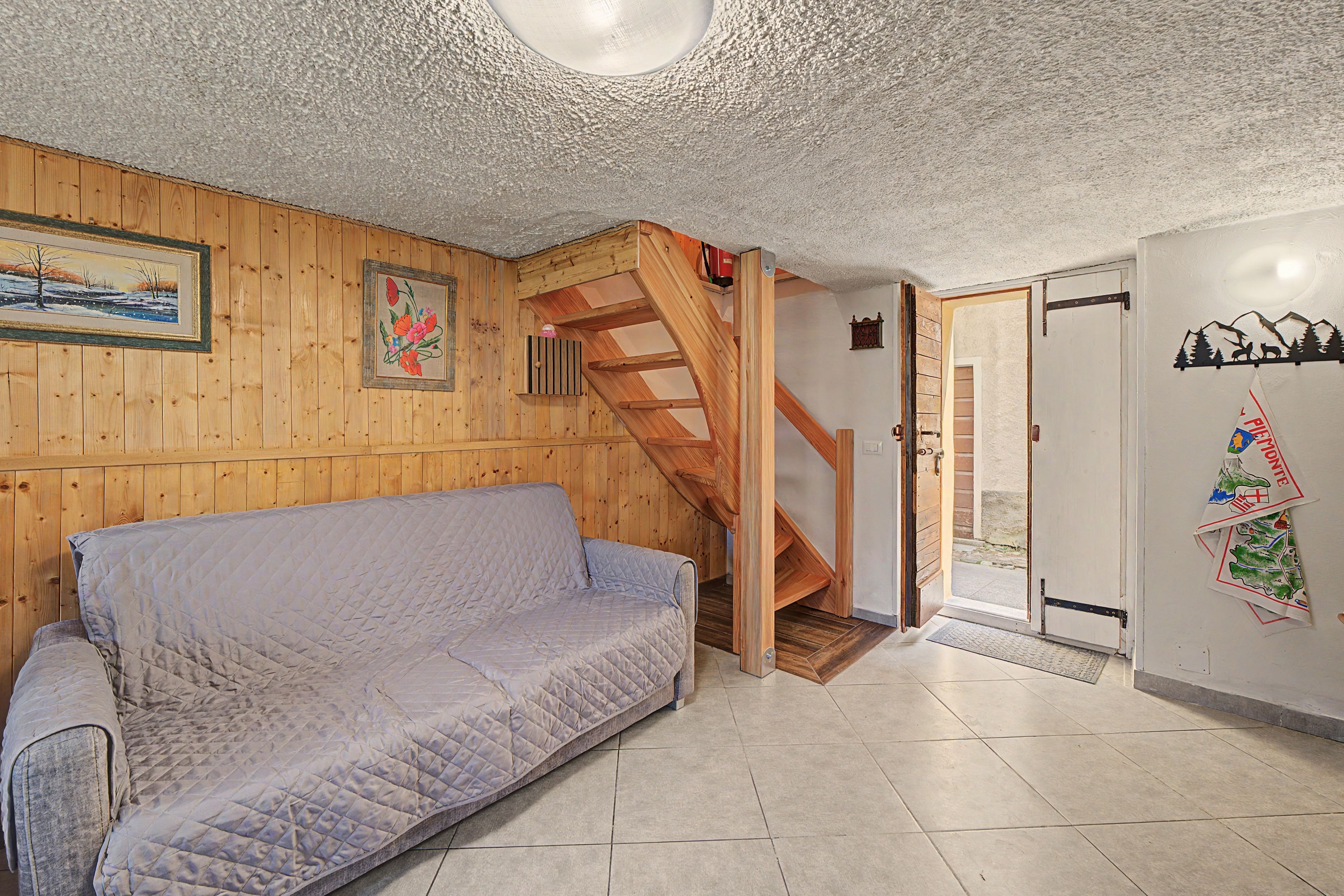 Una habitación con pared de madera, un sofá, una escalera de madera y una puerta decorada con un mapa.