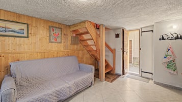 Een kamer met een houten wand, een bank, een houten trap en een deur met een kaartdecoratie.
