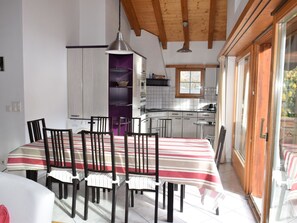 Ein Essbereich mit gestreifter Tischdecke, Stühlen und einer Pendelleuchte.