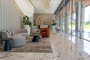 En moderne lobby med en buet sofa, et rundt sofabord og en stueplante.