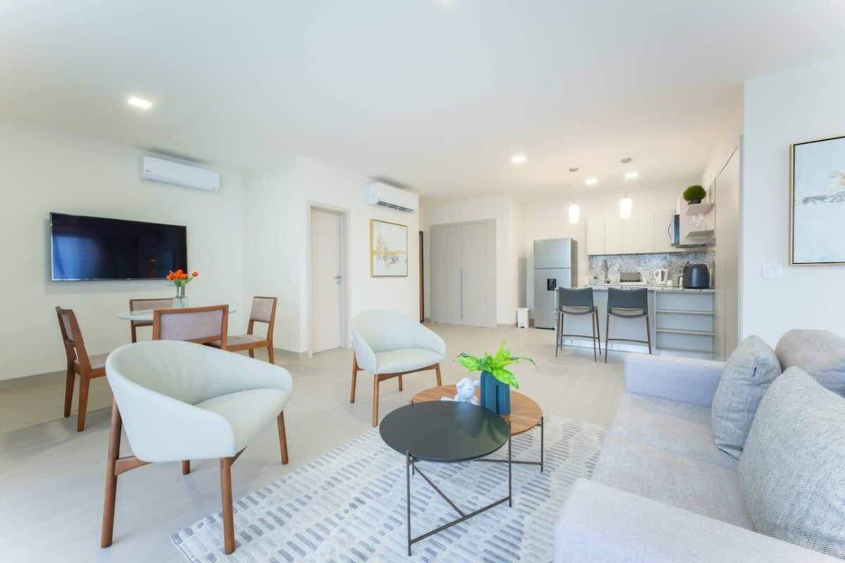 A modern living room with a sofa, chairs, a coffee table, and a TV.