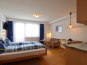 A compact hotel room with a bed, a small sofa, a dining table, and a kitchenette. - Haus Orion Appartement/Fewo 2-Bettwohnung Nr. 7 by Interhome (Saas-Fee)