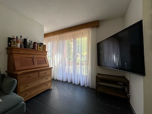 Ein Wohnzimmer mit Holzschrank, Flachbildfernseher und einer Couch.