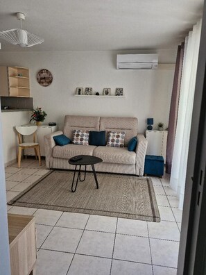 A living room with a sofa, a coffee table, a chair, and a small table with a plant. - Apartment near the beach (Menton)