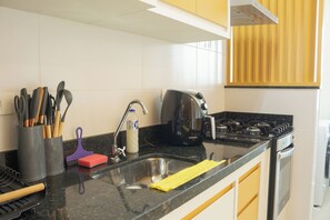 A kitchen with a stainless steel sink, a coffee maker, and various utensils. - Fully furnished apartment in Itagua, 400m from the beach | Swimming pool | Air conditioning & Balcony (Ubatuba)
