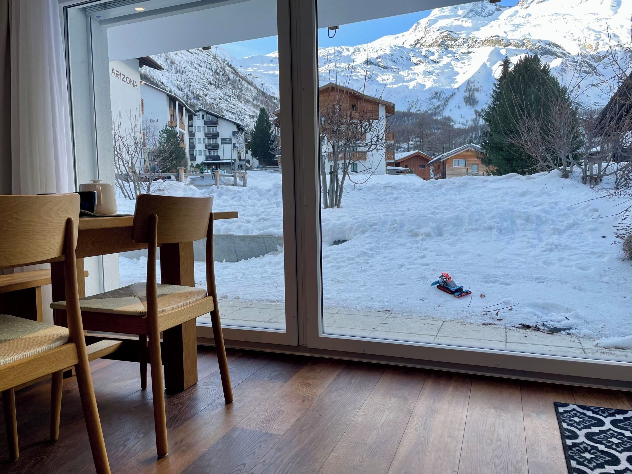 Una habitación con un ventanal grande que da a un paisaje nevado con montañas.