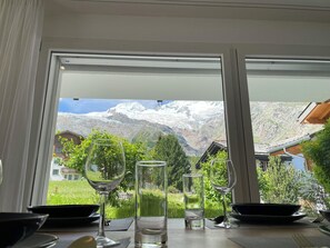 A dining table with wine glasses and a bowl, set against a window with a mountain view. - Romaine Appartement/Fewo Appartement/Fewo by Interhome (Saas-Fee)