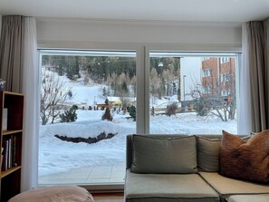 A living room with a large window, a sofa, and a bookshelf. - Romaine Appartement/Fewo Appartement/Fewo by Interhome (Saas-Fee)