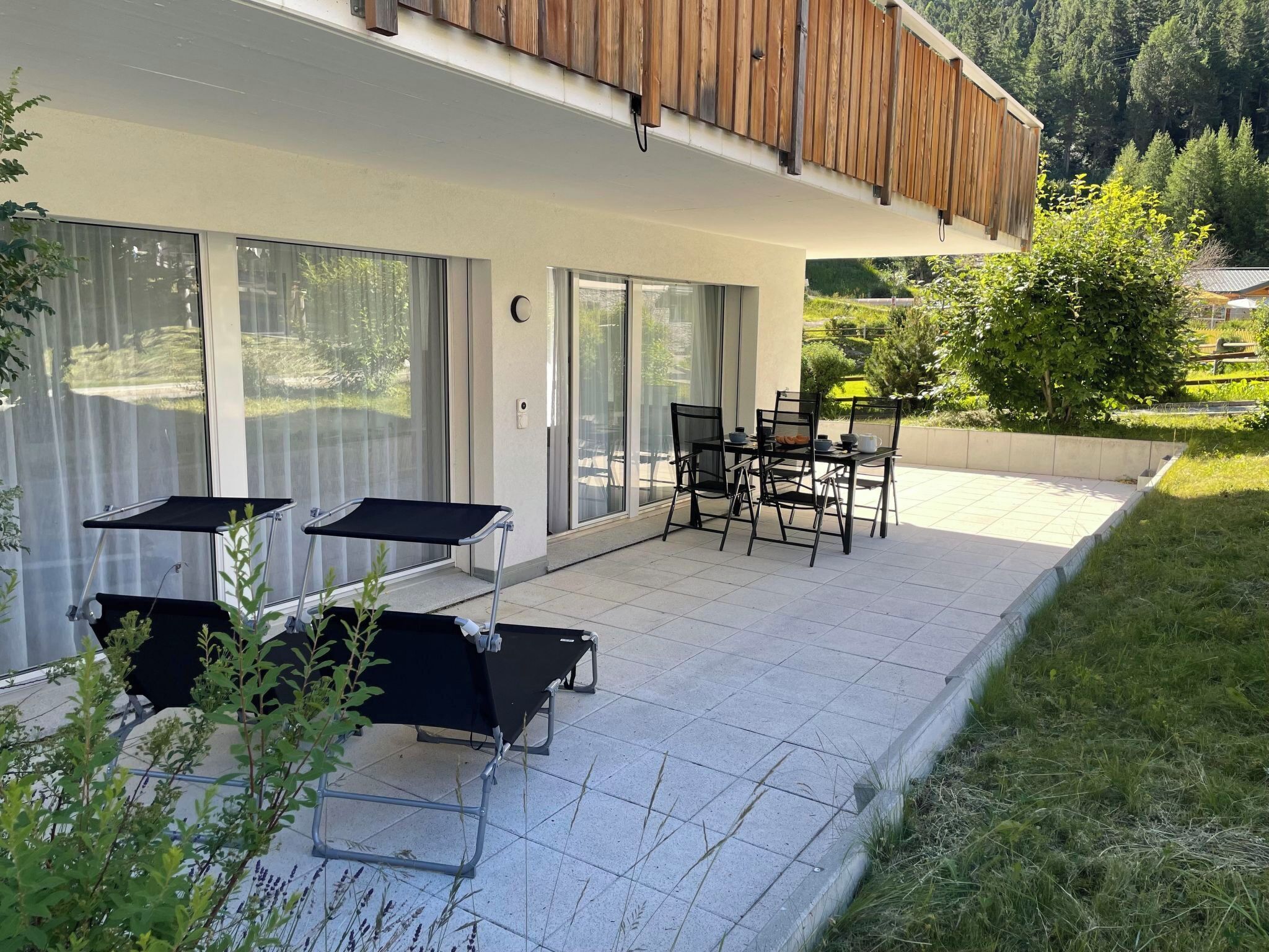 A patio with outdoor furniture, a sliding glass door, and a view of a green landscape.