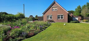 A brick house with a well-maintained lawn and a variety of colorful flowers. - Vacation Rental on the North Sea Coast: Holtgast-Fulkum (Holtgast)