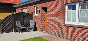 A brick building with a large metal gate, two chairs, and a window with blinds. - Vacation Rental on the North Sea Coast: Holtgast-Fulkum (Holtgast)