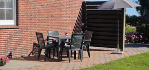 Eine Terrasse im Freien mit einer Ziegelwand, einem Tisch mit Stühlen und einer Holzw pergola.