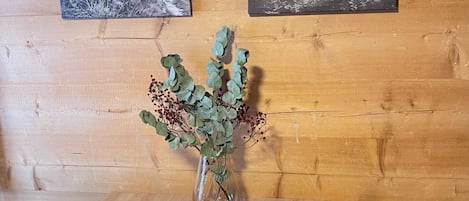 Una mesa de comedor de madera con dos fotografías enmarcadas de fauna, un florero con follaje verde y una mesa puesta con platos, vasos y cubiertos.