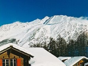 Ein schneebedeckter Berg mit einer Hütte im Vordergrund.