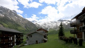 A mountain lodge with a stone facade, wooden balconies, and a view of snow-capped mountains. - Aramis Appartement/Fewo 6-Bettwohnung Nr. 2 by Interhome (Saas-Fee)