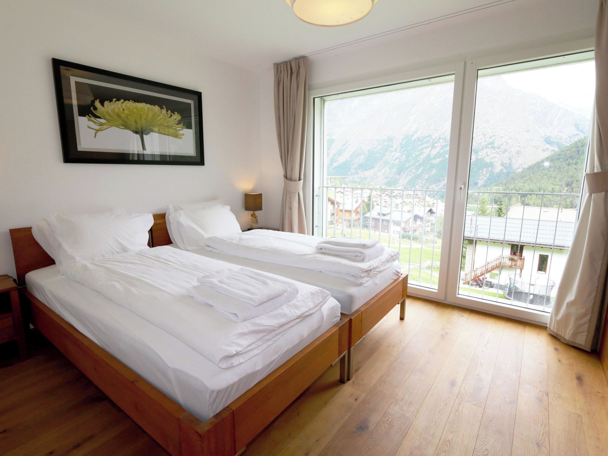 Ein Hotelzimmer mit zwei Betten, einem großen Fenster mit Bergblick und einem gerahmten Bild an der Wand.