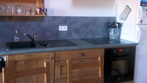 Una cocina con campana extractora negra, un fregadero, armarios de madera y horno empotrado.