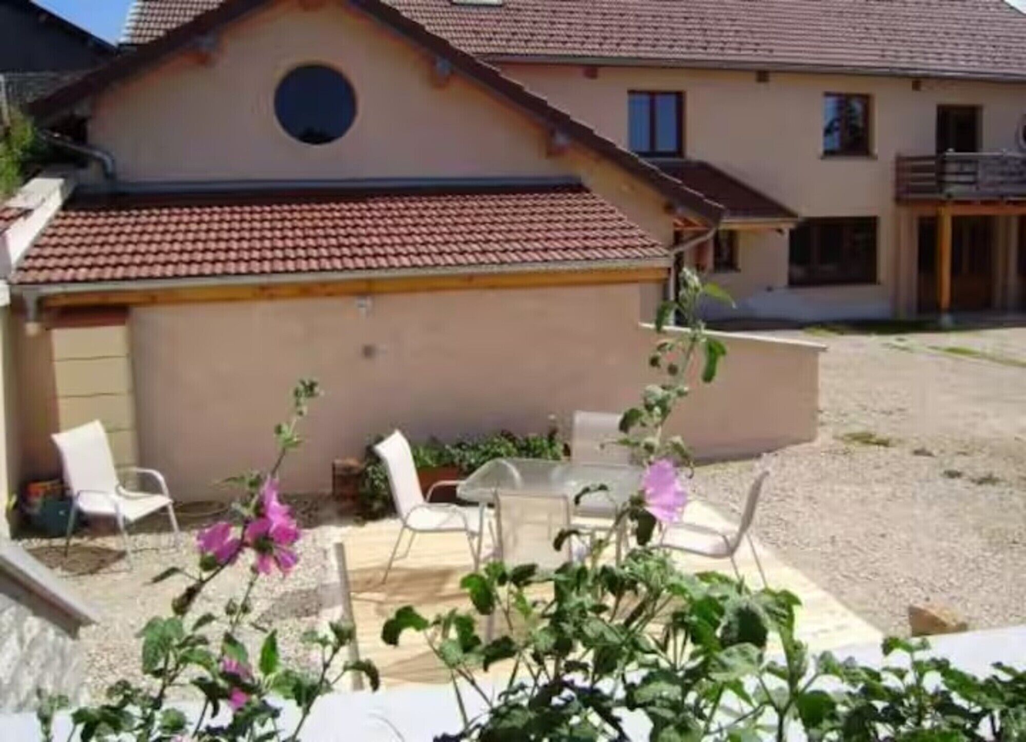 Una casa con un patio, un ventanal redondo y un balcón.