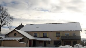Un edificio de dos pisos con techo nevado y un pequeño balcón.