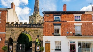 A historic building with a prominent tower, a traditional archway entrance, and adjacent residential buildings. - Stone-Walled 1-Bed with Fireplace · Sleeps 2 by St Edward`s Church, Castle Donington (Castle Donington)