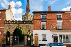 A historic building with a prominent tower, a traditional archway entrance, and adjacent residential buildings. - Stone-Walled 1-Bed with Fireplace · Sleeps 2 by St Edward`s Church, Castle Donington (Castle Donington)