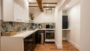 A compact kitchen with white cabinetry, a microwave, an oven, and a sink. - Stone-Walled 1-Bed with Fireplace · Sleeps 2 by St Edward`s Church, Castle Donington (Castle Donington)