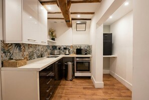A compact kitchen with white cabinetry, a microwave, an oven, and a sink. - Stone-Walled 1-Bed with Fireplace · Sleeps 2 by St Edward`s Church, Castle Donington (Castle Donington)