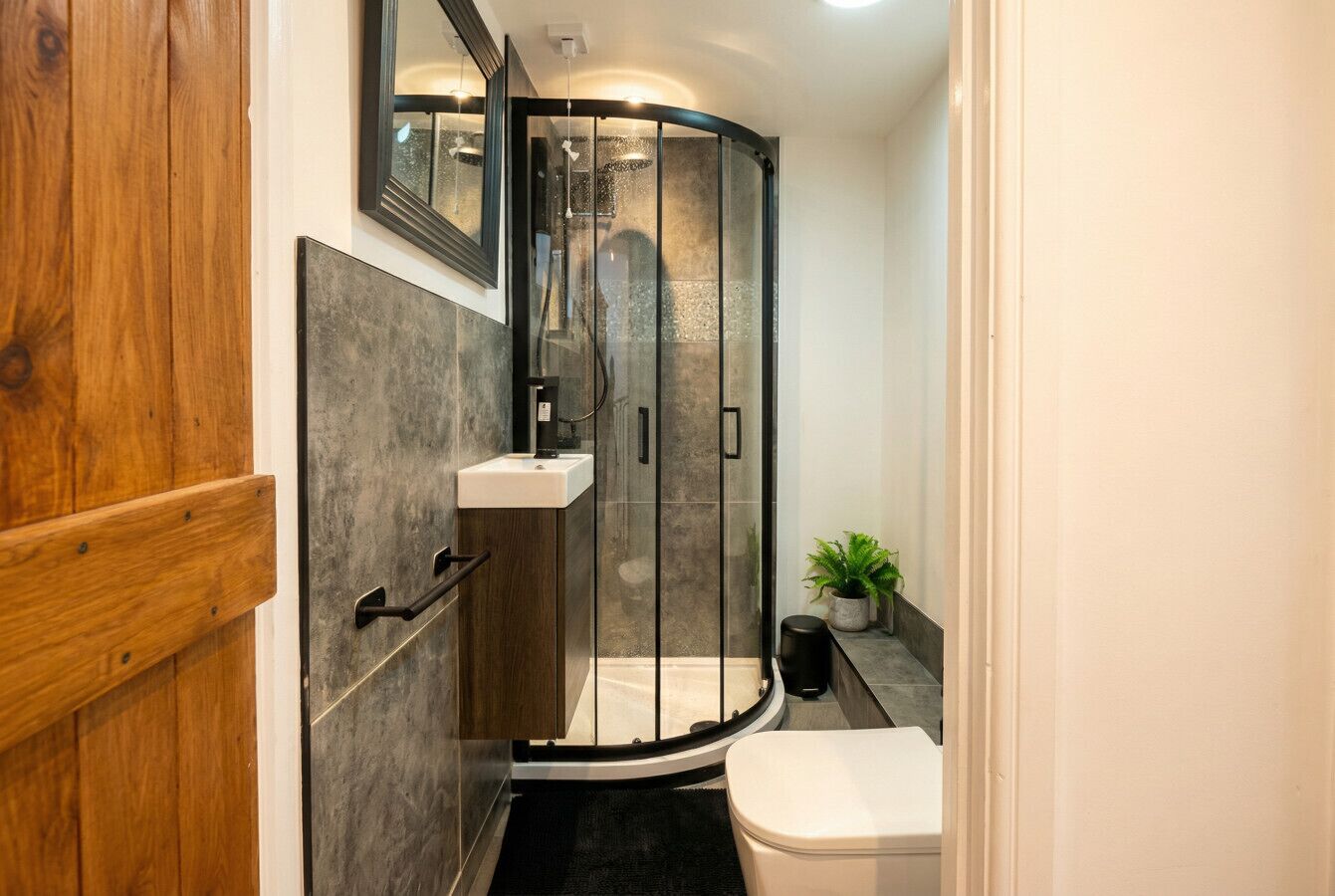 A bathroom with a shower enclosure, a toilet, and a sink.