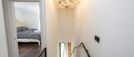 Un escalier menant à une chambre à coucher équipée d’un lit et d’un lustre.