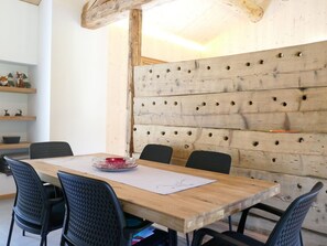 Ein Holzespeisetisch mit vier Stühlen, einem roten Kerzenhalter und einem weißen Blatt Papier darauf.