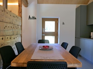 Ein Holztisch mit Stühlen, eine Glasvase und eine Tür mit Fenster.