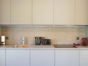 Eine moderne Küche mit Spüle, einer Kaffeemaschine, einem Toaster und einem roten Gerät auf der Arbeitsfläche.