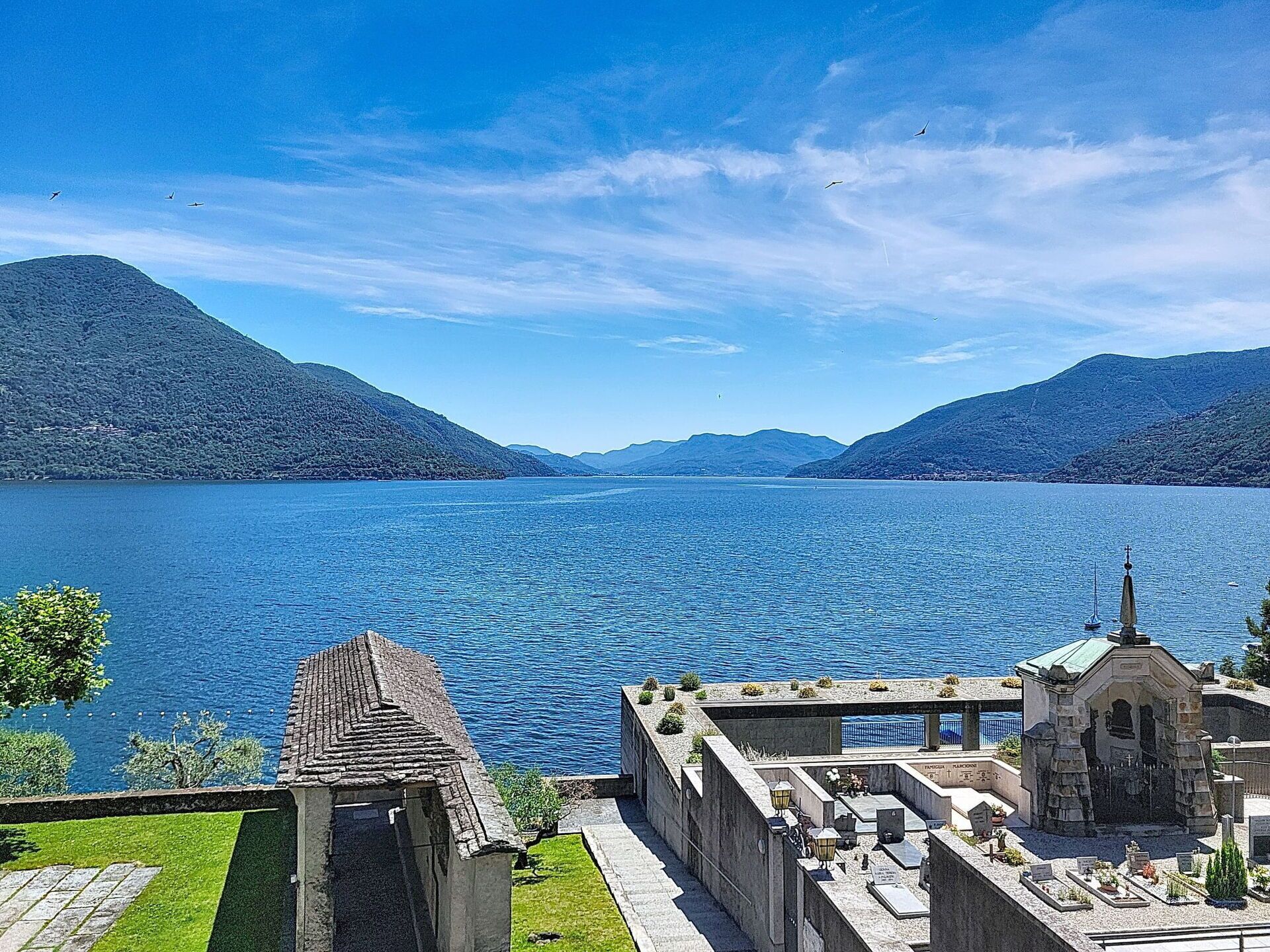 Un lac paisible, avec une église et un cimetière au premier plan, le tout entouré de montagnes.