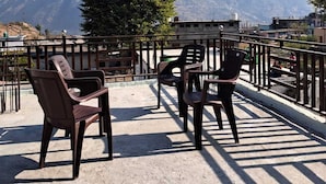 Une terrasse avec des chaises et des tables, d’où l’on a une vue sur la montagne.