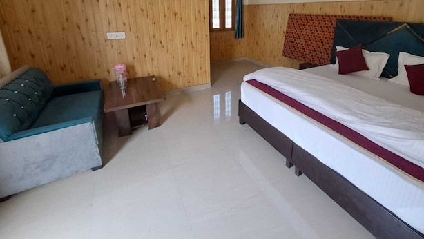 Una habitación de hotel con cama, sofá, una mesita y paredes de madera.