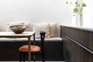 A corner seating area with a wooden bowl on a table, a cushioned bench, and a potted plant on a windowsill. - Emery Hill Street by onefinestay (London)
