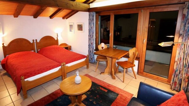 Ein Schlafzimmer mit zwei Betten, einem kleinen Tisch, einem Stuhl und einem Sofa.